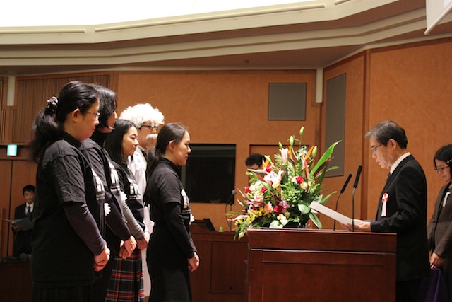 濱田総長から表彰状を受け取る田村ワーキンググループ代表（中央）